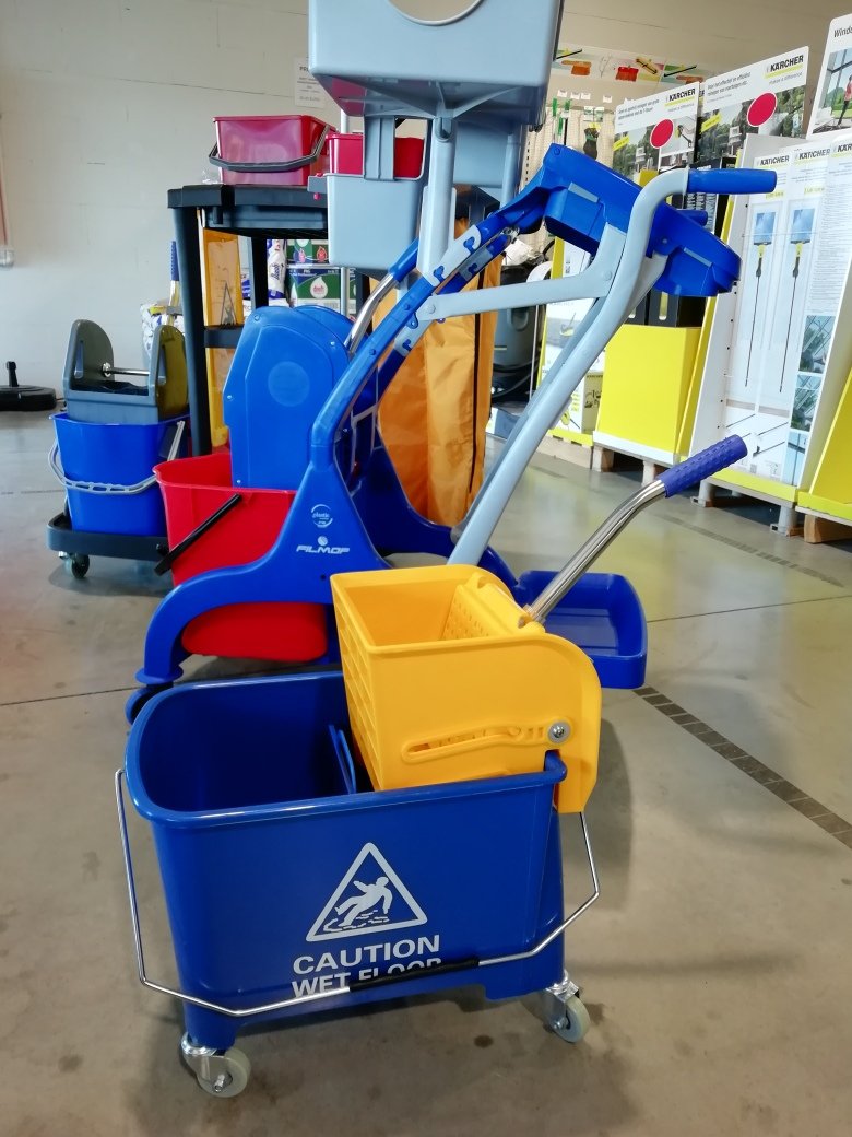 Blue janitorial cart with a yellow mop basket and a blue wet-floor bucket, on a store floor in a showroom.